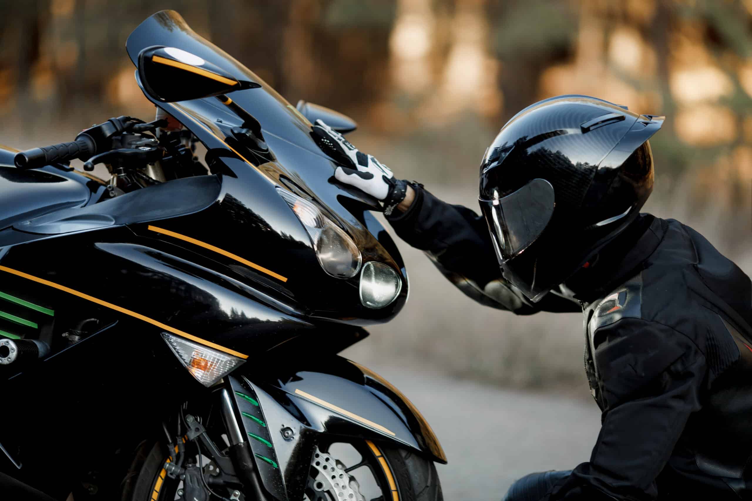 Rider in protective gear inspecting his bike to avoid needing a motorcycle accident lawyer